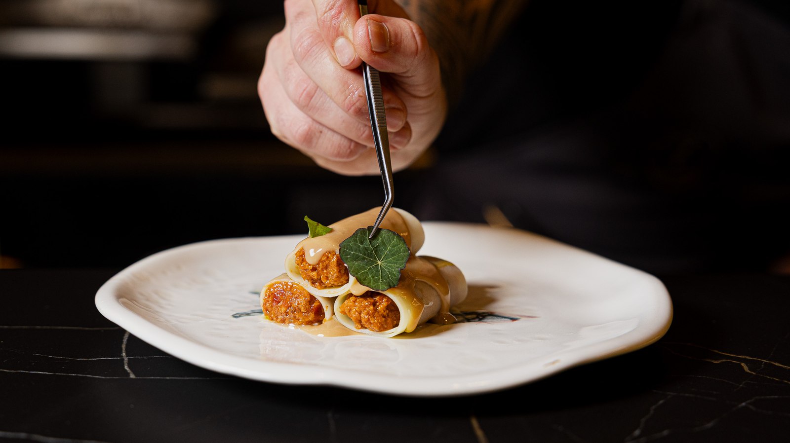 Emplatado con pinzas de un plato de canelones en la cocina de Salitre